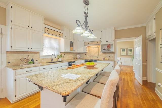 kitchen with white cabinets, sink, a kitchen island, and light hardwood / wood-style floors