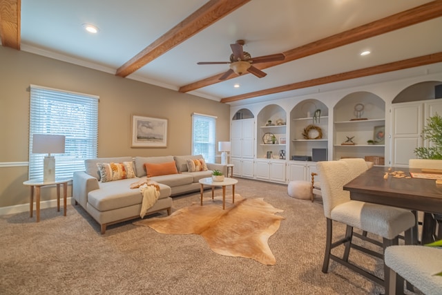 carpeted living room featuring beam ceiling, ceiling fan, a healthy amount of sunlight, and ornamental molding