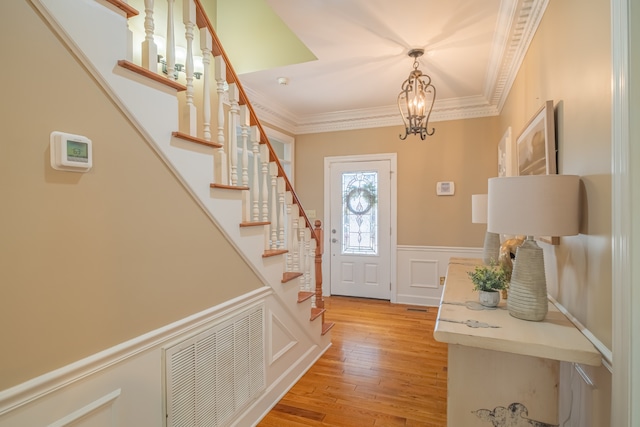 entrance foyer featuring a chandelier, crown molding, and light hardwood / wood-style floors