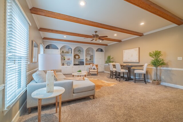 carpeted living room featuring beamed ceiling, ceiling fan, and crown molding