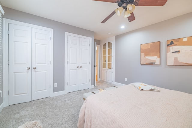 carpeted bedroom featuring ceiling fan and multiple closets