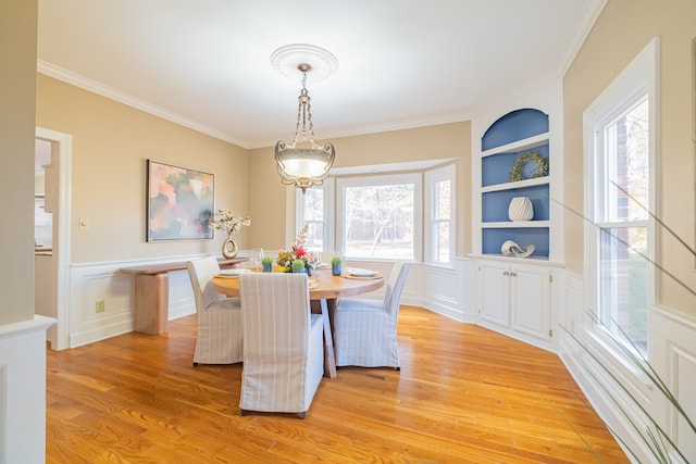 dining room with light hardwood / wood-style flooring, built in features, plenty of natural light, and ornamental molding