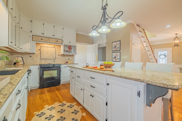 kitchen with a kitchen breakfast bar, black / electric stove, light hardwood / wood-style flooring, and white cabinets