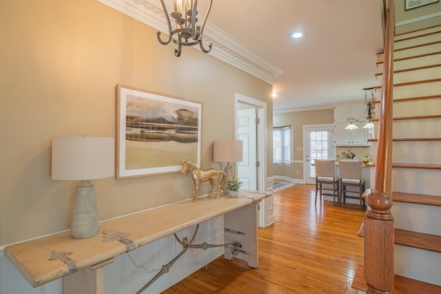 hall featuring a notable chandelier, light hardwood / wood-style floors, and ornamental molding