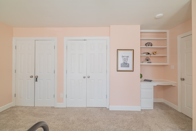 unfurnished bedroom featuring two closets and light colored carpet