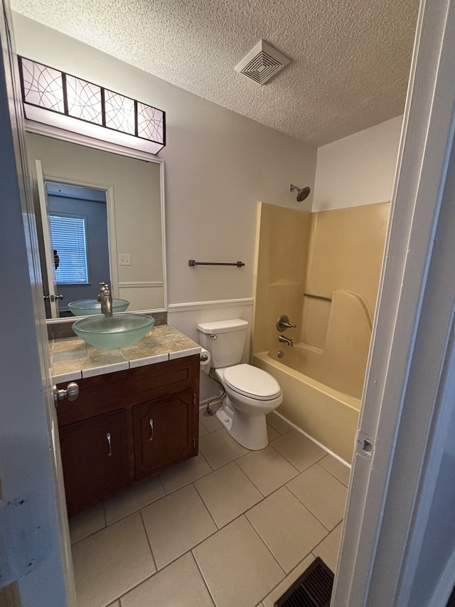 full bathroom featuring tub / shower combination, a textured ceiling, vanity, tile patterned flooring, and toilet