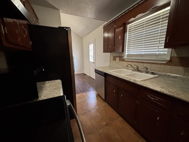 kitchen with sink, stainless steel dishwasher, vaulted ceiling, a textured ceiling, and decorative backsplash