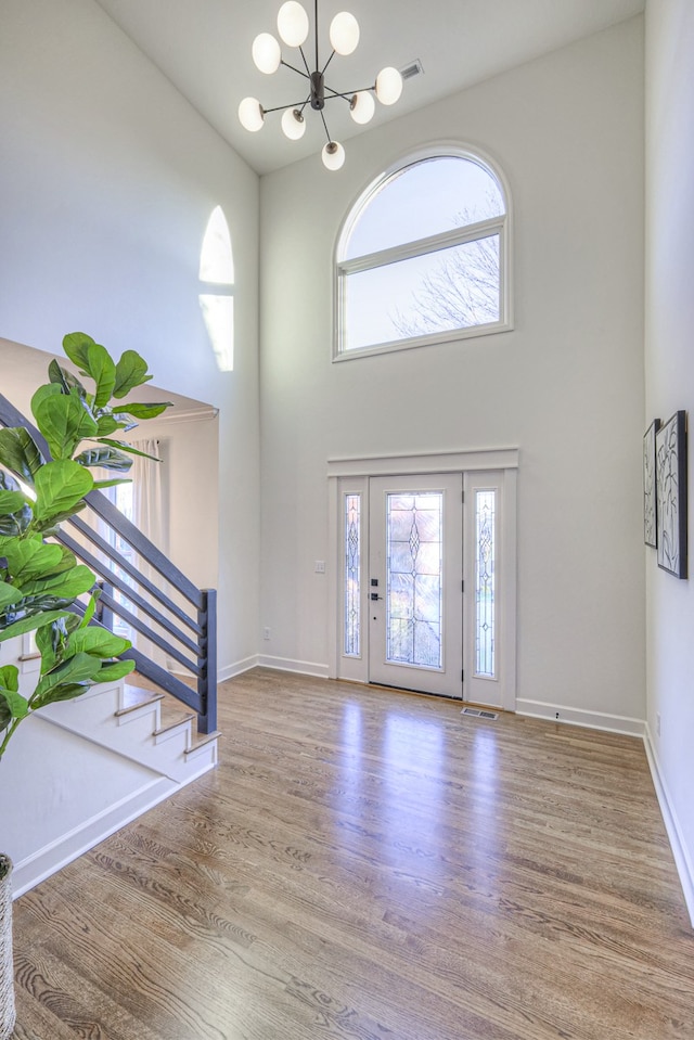 entryway featuring hardwood / wood-style floors, a high ceiling, and an inviting chandelier