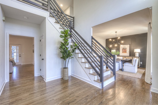 staircase featuring a chandelier, a high ceiling, and hardwood / wood-style flooring