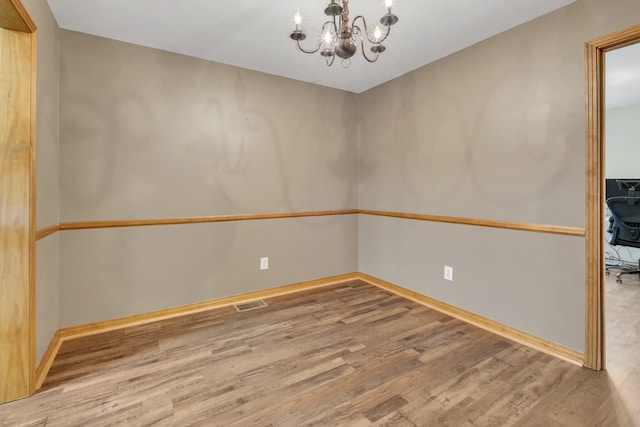 empty room featuring a notable chandelier and hardwood / wood-style flooring