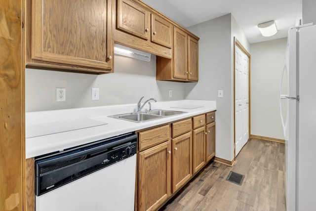 kitchen with white appliances, hardwood / wood-style flooring, and sink