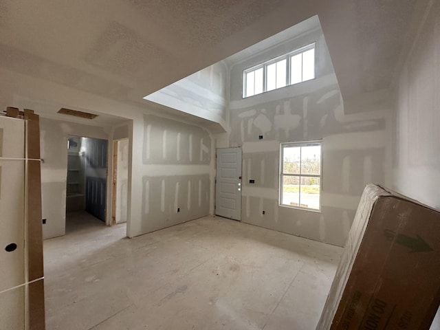 empty room with a textured ceiling and a towering ceiling