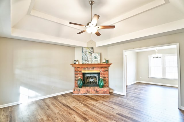 unfurnished living room featuring a fireplace, ceiling fan with notable chandelier, and hardwood / wood-style flooring