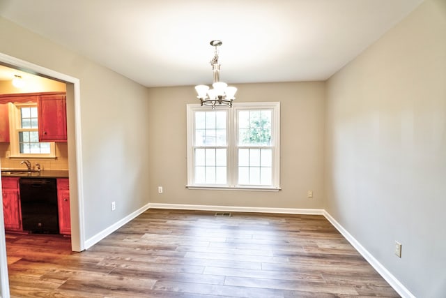 unfurnished dining area featuring hardwood / wood-style floors, sink, and an inviting chandelier