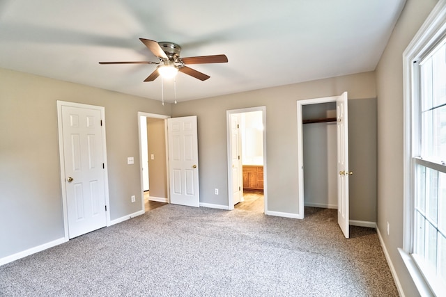 unfurnished bedroom featuring ceiling fan, light colored carpet, connected bathroom, and two closets