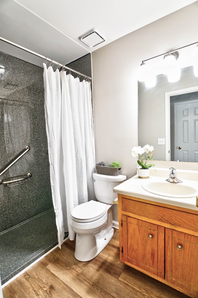 bathroom with wood-type flooring, vanity, toilet, and walk in shower