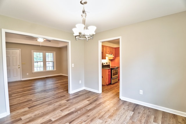 unfurnished dining area with ceiling fan with notable chandelier and light hardwood / wood-style floors