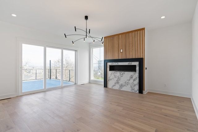 unfurnished living room with a notable chandelier and light hardwood / wood-style floors