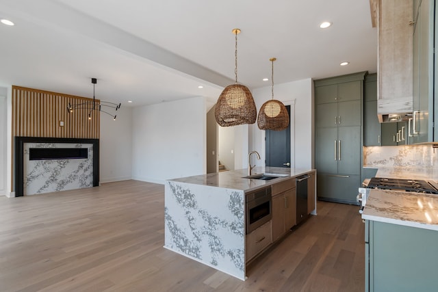 kitchen with pendant lighting, hardwood / wood-style flooring, a kitchen island with sink, and sink