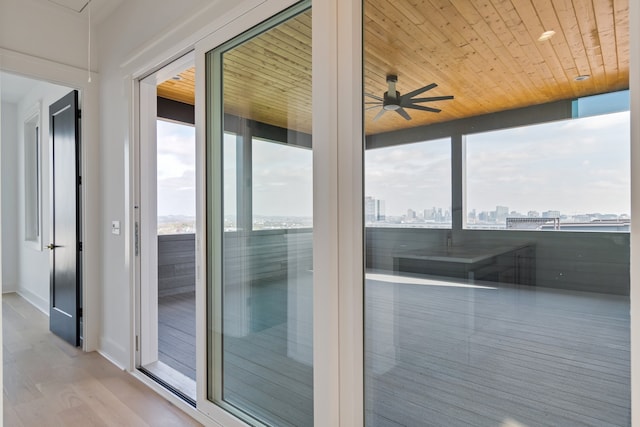 doorway with light hardwood / wood-style floors, ceiling fan, and wooden ceiling