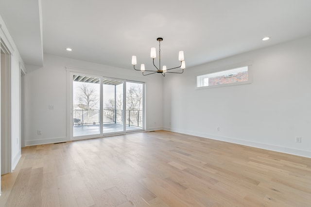 unfurnished room with a chandelier, light wood-type flooring, and plenty of natural light