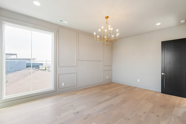 unfurnished room with a chandelier and light wood-type flooring