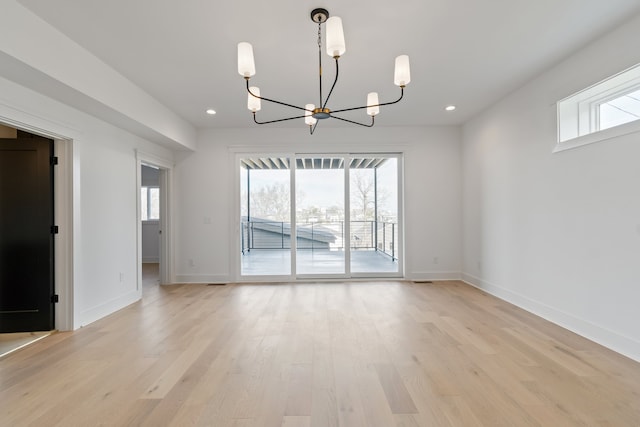 unfurnished dining area with a chandelier, light wood-type flooring, and plenty of natural light