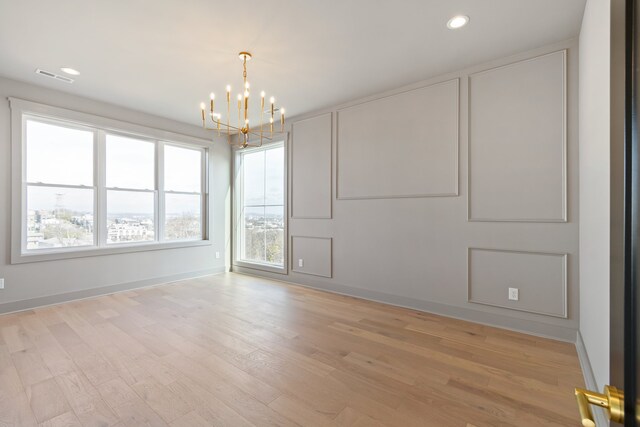 unfurnished room featuring a chandelier and light wood-type flooring