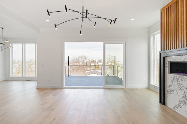 unfurnished living room with a chandelier and light hardwood / wood-style flooring