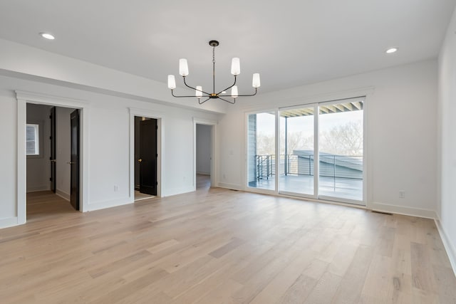 empty room featuring an inviting chandelier and light wood-type flooring