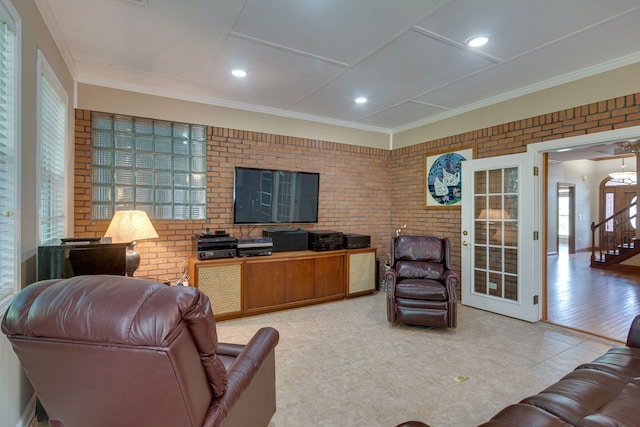 living room with crown molding, light hardwood / wood-style flooring, and brick wall