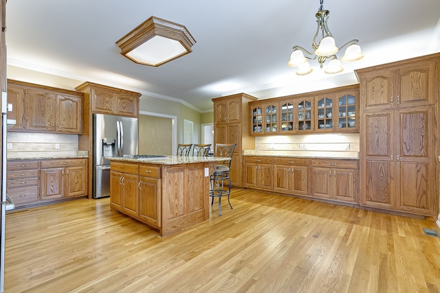 kitchen featuring light stone countertops, a chandelier, pendant lighting, light hardwood / wood-style floors, and a kitchen island