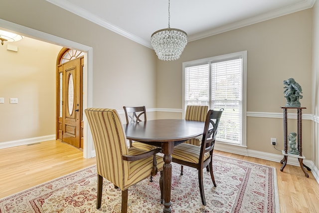 dining area featuring light wood-type flooring, crown molding, and a notable chandelier