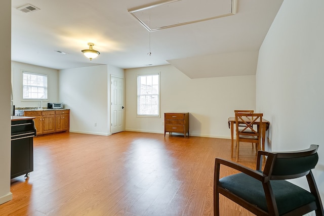 living area with a wealth of natural light, sink, and light hardwood / wood-style floors