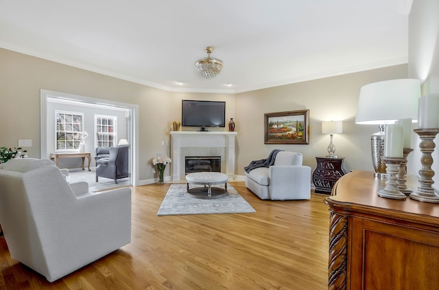 living room featuring light wood-type flooring, crown molding, and a tiled fireplace