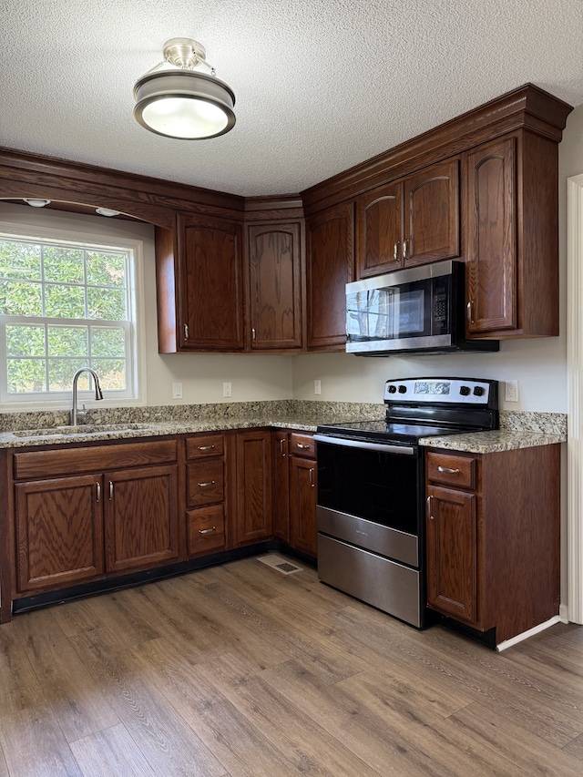 kitchen featuring light stone counters, sink, stainless steel appliances, and dark hardwood / wood-style floors