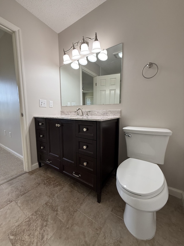 bathroom featuring vanity, toilet, and a textured ceiling