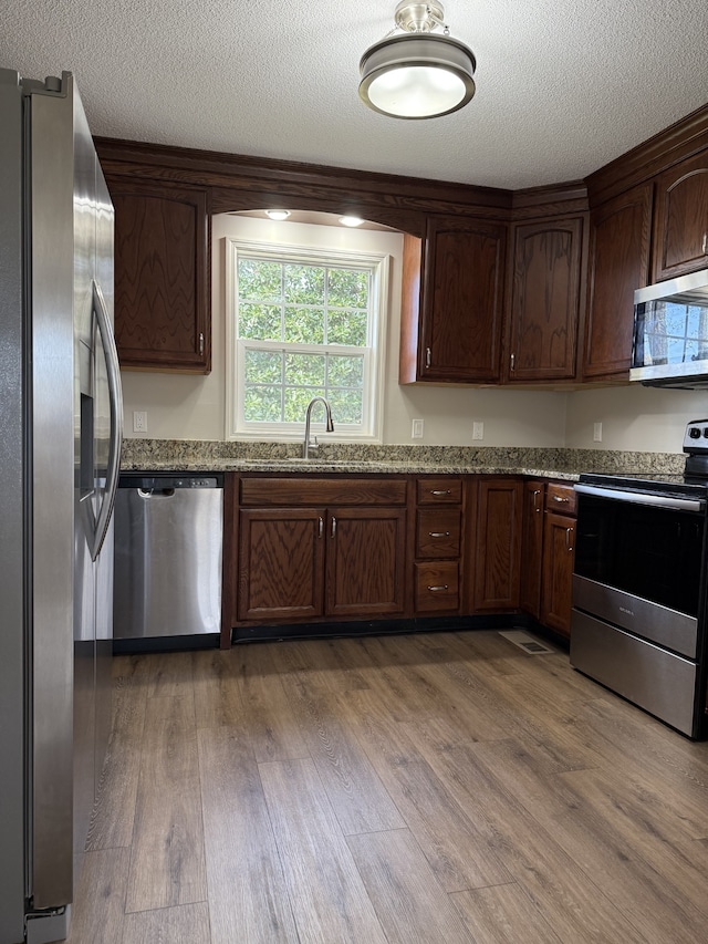 kitchen featuring light stone counters, stainless steel appliances, and hardwood / wood-style flooring