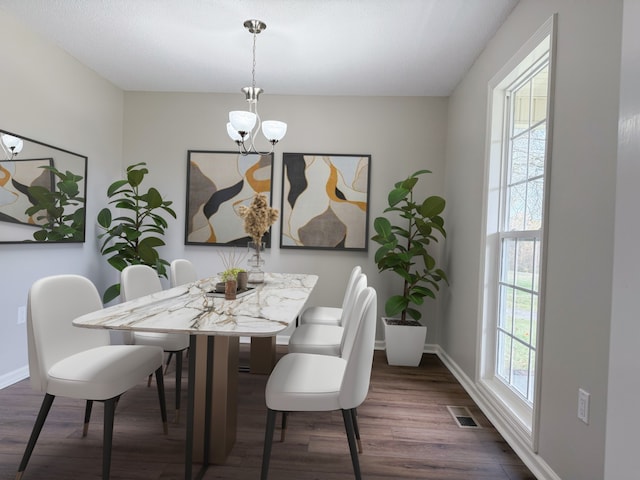 dining space featuring dark wood-type flooring and a notable chandelier