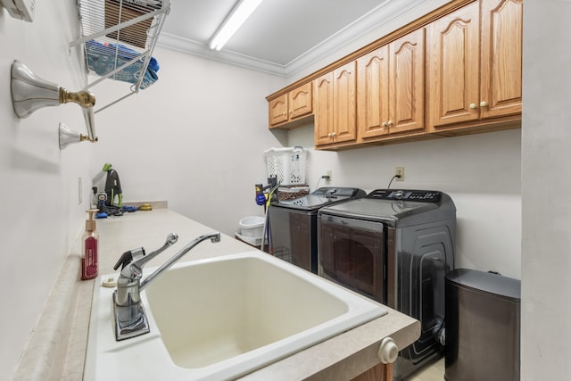 laundry room with washing machine and dryer, crown molding, sink, and cabinets