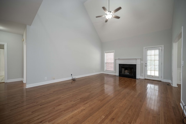 unfurnished living room featuring ceiling fan, high vaulted ceiling, a healthy amount of sunlight, and dark hardwood / wood-style floors