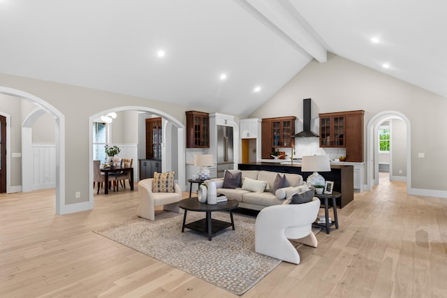 living room with beam ceiling, light wood-type flooring, and high vaulted ceiling