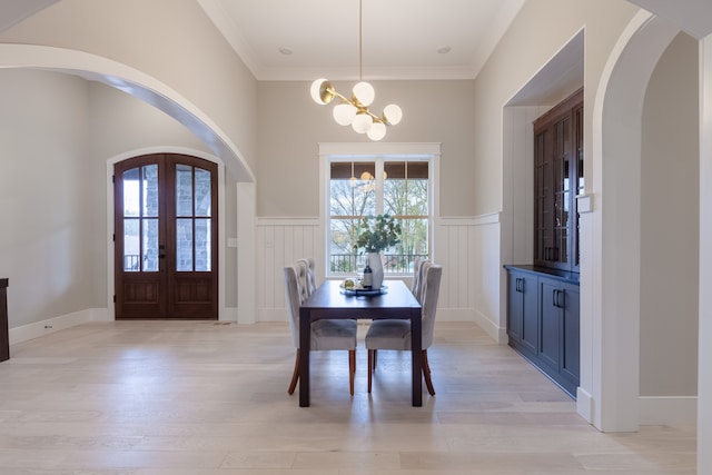 dining room with a wealth of natural light, french doors, an inviting chandelier, and light wood-type flooring