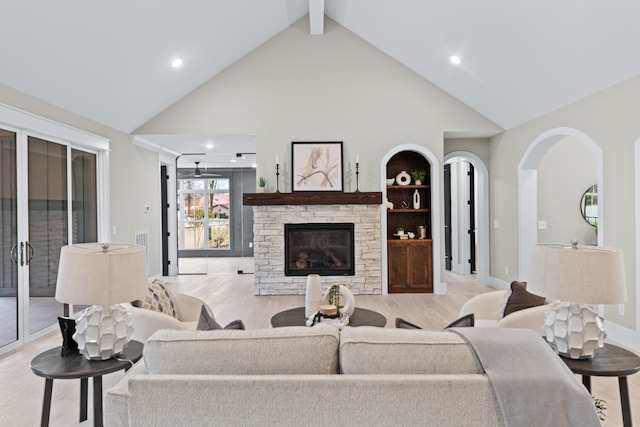 living room with a fireplace, beam ceiling, high vaulted ceiling, and light hardwood / wood-style flooring