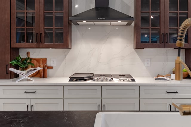 kitchen featuring white cabinets, tasteful backsplash, stainless steel gas cooktop, and wall chimney range hood