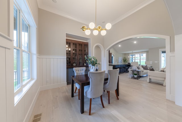 dining room with light hardwood / wood-style floors, crown molding, and an inviting chandelier