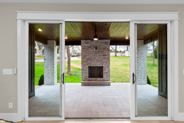 doorway with ceiling fan, a healthy amount of sunlight, and an outdoor stone fireplace