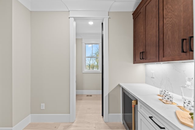 interior space with tasteful backsplash, dark brown cabinets, and light hardwood / wood-style floors