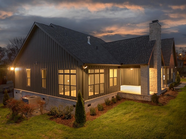 back house at dusk featuring a yard, a patio, and central AC unit