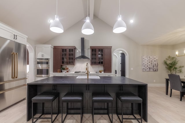 kitchen featuring appliances with stainless steel finishes, wall chimney exhaust hood, and an island with sink